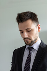 Young man with a beard in a suit looks down. Face closeup