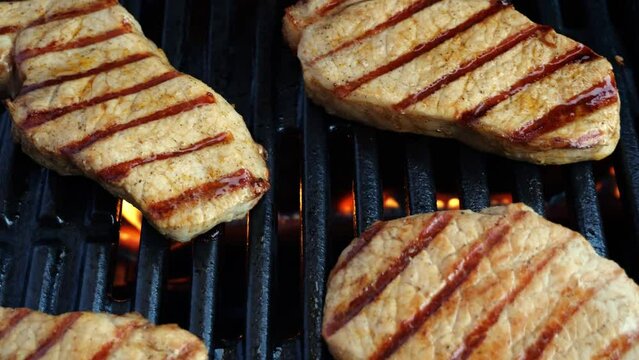 Grilled cooking pork loin chops and potatoes wedges on grill, barbecue, hot cast iron. close up