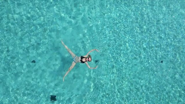 Top view of young woman swimming on the back in the pool in slow motion.