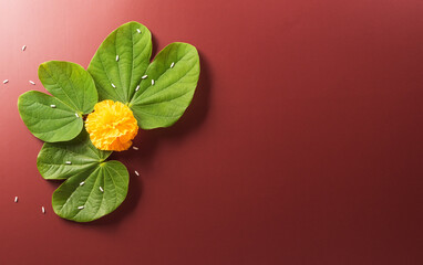 Happy Dussehra. Yellow flowers, green leaf and rice on dark paper background. Dussehra Indian Festival concept.