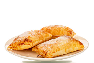Three fragrant puff pastry buns with apples on a white ceramic plate, close-up, isolated on a white background.