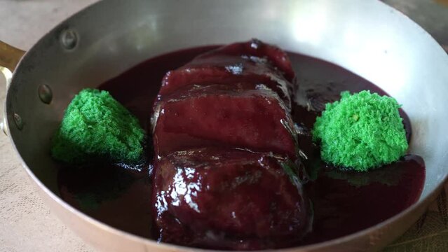 Veal with cherry sauce with tarragon in a frying pan. Beautiful restaurant serving food. Appetizing food on a plate. 