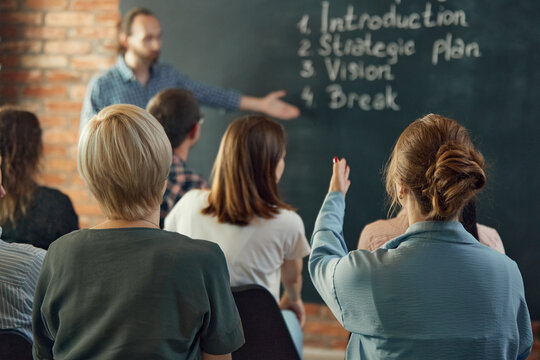 Speaker giving talk at business meeting near green board. Audience in the conference hall. Strategy and planning is success.