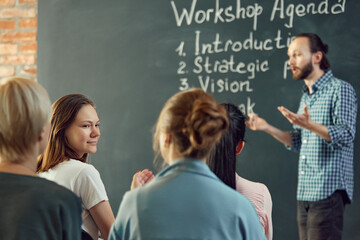 Business and entrepreneurship symposium. Speakers giving talk at business briefing. Rear view of unrecognized participant in audience.