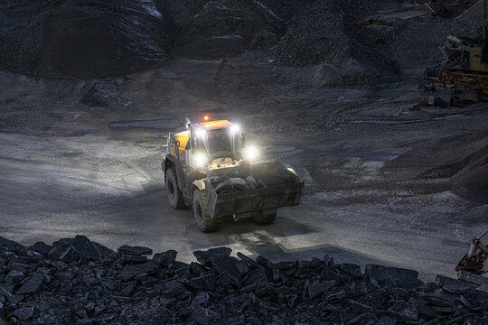 Illuminated bulldozer carrying stones in quarry
