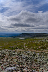 Fototapeta na wymiar In the middle of Scandinavian nature, elevated view from rocky mountain peak or outcrop view of tundra valley landscape and mountain with cloudscape in a remote national park of Dalarna Sweden