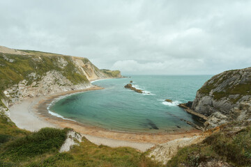 A crescent-shaped sea cove surrounded by a rocky coastline and beach on the Dorset coast in southern England. Located next Durdle Door. Man O' War Beach. High quality photo