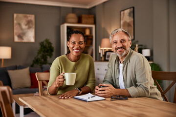 A diverse couple happily sipping tea at their table, facing the camera.
