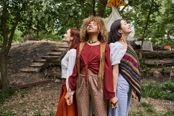 cheerful african american woman holding hands of girlfriends outdoors in retreat center