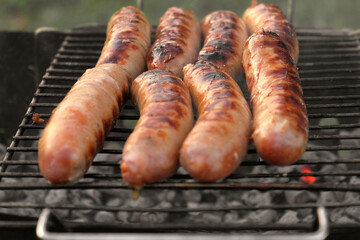 Grilled sausages. Cook man preparing grilling food bbq. Barbecue with smoke, flame outdoors. Tasty...