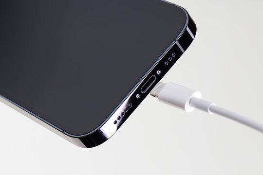 Bottom part of IPhone 14 pro and proprietary lightening charger cable. Outdated charging and data communication technology. IPhone 14 pro smartphone. Apple gadgets.