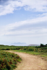 Hiking trail leading to the sea with island on the horizon.