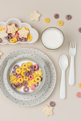 Colorful cereal rings with milk in bowl. Dry children's breakfast. Cute children's plates and bowls with tasty food. Creative serving for baby. Concept of kids menu, nutrition and feeding.