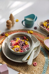 Colorful cereal rings with milk in bowl. Dry children's breakfast. Cute children's plates and bowls with tasty food. Creative serving for baby. Concept of kids menu, nutrition and feeding.