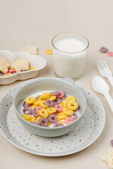 Colorful cereal rings with milk in bowl. Dry children's breakfast. Cute children's plates and bowls with tasty food. Creative serving for baby. Concept of kids menu, nutrition and feeding.