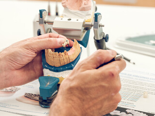 Crop dental technician working with articulator while making den