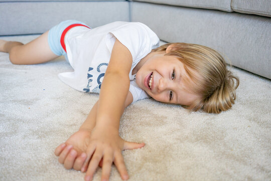 portrait of a little boy smiling lying on a carpet at home