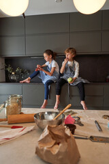 Children eating fruits while sitting on complete kitchen