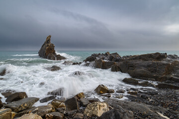 Fototapeta na wymiar Seascape image of white waves rushing up the rocky beach