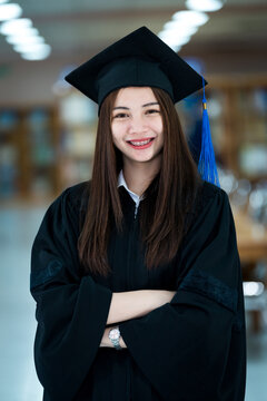 Portrait young happy and excited Asian woman university graduate in graduation gown and cap in the library. Education stock photo
