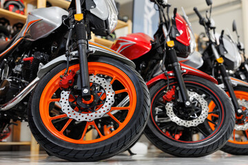There are many colorful motorcycles for sale in exhibition hall. Wheels close-up.