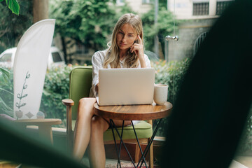 Remote working woman typing on a laptop while sitting in a coffee shop.