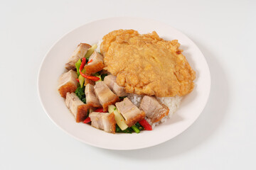 A close-up shot of food is called Crispy Pork with Kale topped with rice in dish and Stuffed omelet.crispy pork, basil and delicious omelette in a white plate 