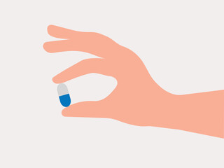 Human hand holding a pill capsule in blue and white color
