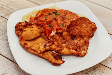 Plato de pechuga de pollo rebozada y frita, acompañada de espaguetis con tomate