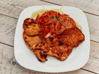 Plato de pechuga de pollo rebozada y frita, acompañada de espaguetis con tomate