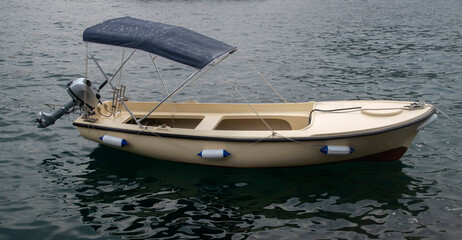 A small fiberglass boat with motor and awning in water in Montenegro