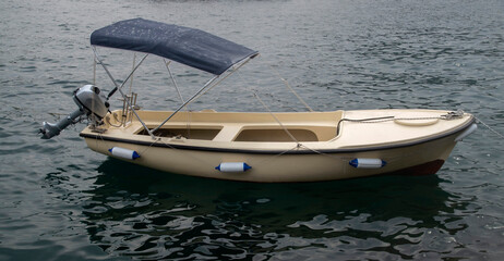 Naklejka premium A small fiberglass boat with motor and awning in water in Montenegro