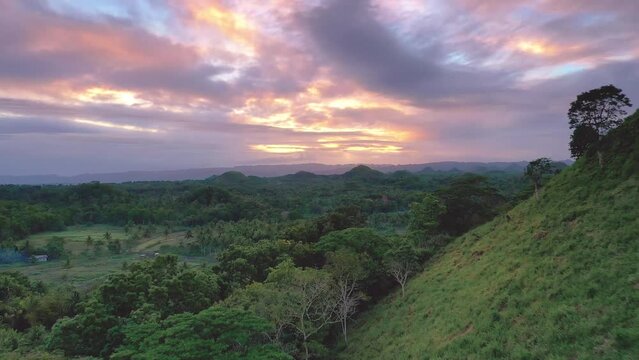 Chocolate Hills at sunset in Bohol, Philippines. Low altitude aerial travelling. Cinematic drone shot panning down at famous landmark travel destination.