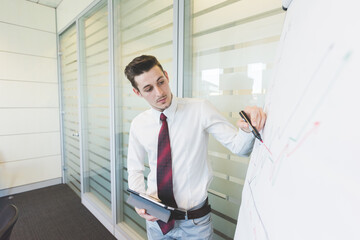 Fototapeta premium Young businessman writing diagram using tablet