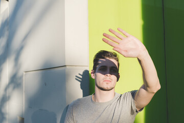 Obraz premium Man hiding sun with hand posing outdoors