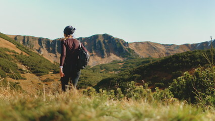 Tourist woman hike trekking trail in autumn mountains. Girl with backpack walking highland meadow...