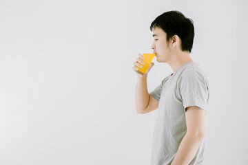 Selective focus shot of a young Asian man is drinking vitamin c water while facing on the left side. Isolated white background.