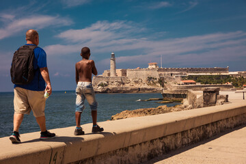 Un turista caminando con un niño por el paseo del malecón en la Habana Cuba. - obrazy, fototapety, plakaty