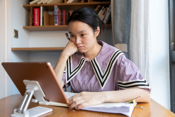 A young Chinese woman is learning on a tablet at home