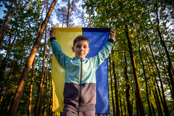 Worried teenager patriot wear blue yellow Ukrainian flag on his shoulders. Spring nature...