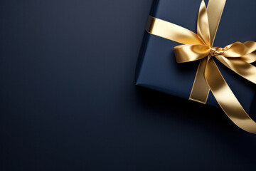 Dark blue gift box, gold satin ribbon on dark background. Ideal for holiday or Christmas present with copy space.