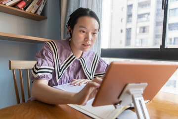 A young Chinese woman is learning on a tablet at home