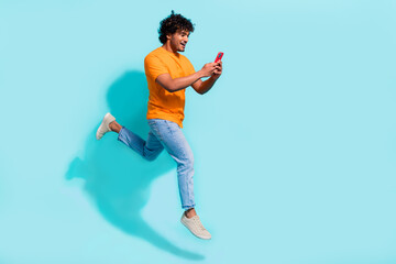 Fototapeta na wymiar Full size profile portrait of crazy carefree guy jumping rush empty space use smart phone isolated on turquoise color background