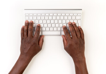 Top view of black male typing on computer keyboard while working