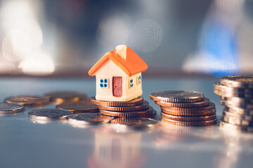 Miniature orange house on stack coins using as property real estate and business financial concept