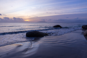 Fototapeta na wymiar Seaside landscape with wet sand and coastal stones at sunset. Seychelles