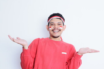 Fototapeta premium Happy excited face asian man showing something with his hand, isolated on white background for advertisement. celebrating Indonesia independence day.