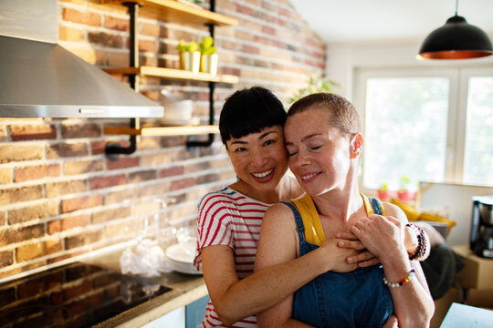 Portrait Of A Young Smiling Lesbian Couple Looking At Camera After Moving In Their New Home Apartment