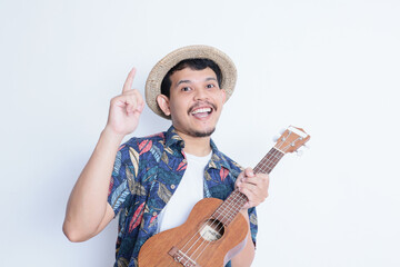 a young man in a beach suit holding a ukulele and smiling at the camera. vacation and traveling concept
