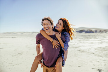 Middle aged caucasian couple walking and having fun on a beach during their vacations